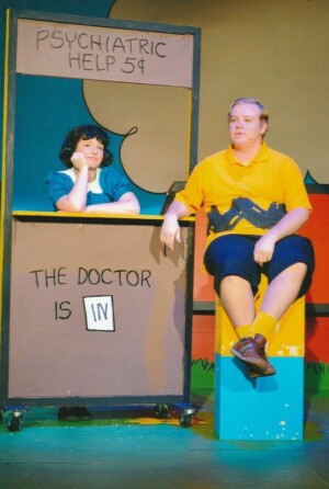 Lucy running a popup psychiatric booth giving advice to Charlie Brown