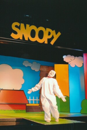 Snoopy on set, standing under a sign with his name