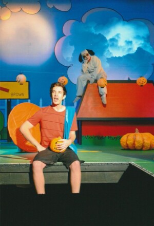 Linus singing with Snoopy sitting on his kennel. Halloween and there are carved pumpkins everywhere.
